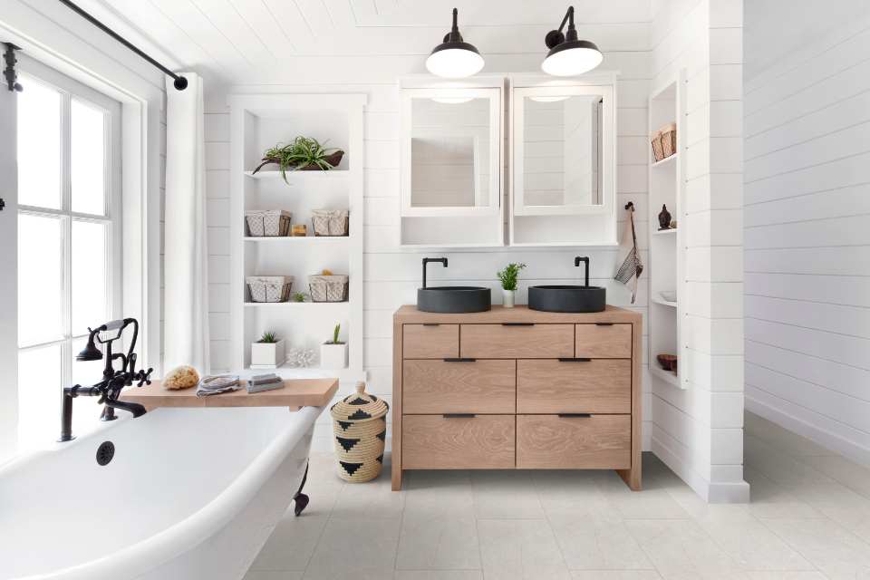 white stone look flooring in all white farmhouse bathroom with clawfoot tub and extra built in shelving